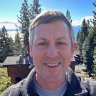 Ken Werner in front of cabin and forest